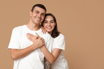 Poster - Cheerful young couple hugging on beige background