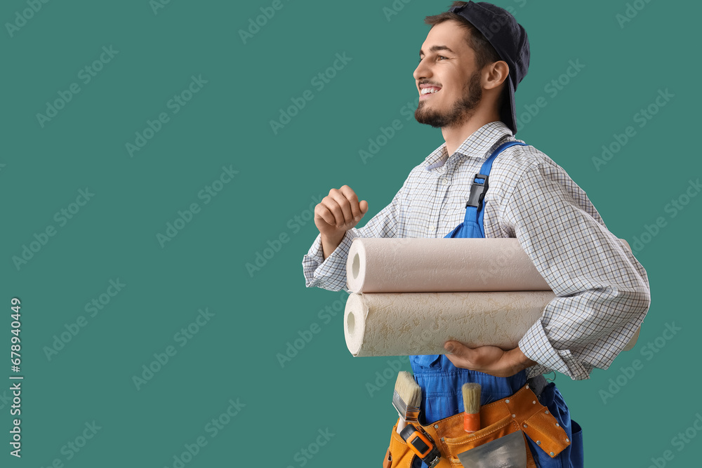 Male decorator with wallpaper rolls on green background