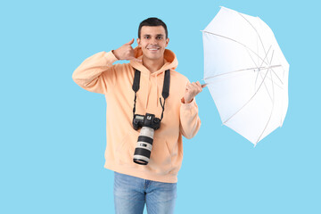 Wall Mural - Male photographer with camera and lighting equipment showing 