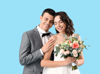 Poster - Young wedding couple with bouquet of flowers on blue background