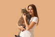 © Pixel-Shot - Pretty young woman with cute tabby cat on beige background
