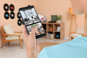 Canvas Print - Woman using smart home security system on mobile phone indoors, closeup. Device showing different rooms through cameras