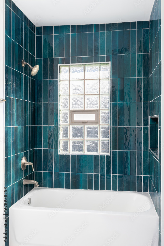 A bathroom shower detail with vibrant blue vertical glass subway tiles ...