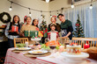 © artitwpd - Happy and cheerful Asian family gathering, wearing Santa hats talking and smiling. Exchanging gifts, grandparents, grandchildren, daughters, at Christmas dinner table with decorated Christmas tree.