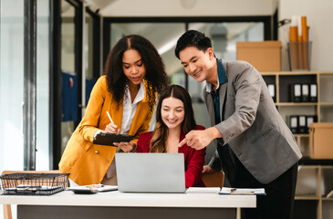 Diverse group of three professionals, two women and man, working together on design project around laptop. Product design team for industrial, working together, Asian man, African american people