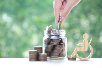 Poster - Man on wheelchair and coin money in the glass bottle on natural green background,Save money for prepare in future and handicapped person concept