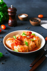 Wall Mural - Stuffed cabbage rolls with meat and rice, with tomato souce in a plate on a dark background