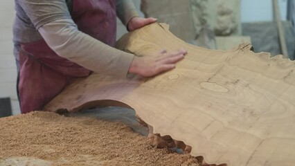 Wall Mural - A craftsman's hand caresses the smooth surface of a timber cut, ensuring quality. The image symbolizes the hands-on approach in traditional woodworking.