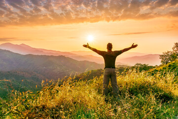 rejoicing man with beautiful scenic mountain sunset landscape on background. happy man watching amazing evening sunset