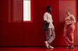 © Seventyfour - Minimal side view portrait of two contemporary young people talking while leaning on wall in futuristic red office space