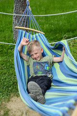 a little boy lies in a hammock in a recreation area against the backdrop of a beautiful mountain lan