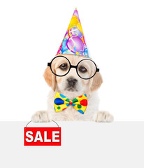Poster - Funny Golden retriever puppy wearing tie bow, eyeglasses and party cap shows signboard with labeled 