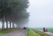 traffic on bicycle and car to school and work during morning mist in the netherlands near utrecht