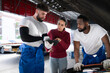 © Wosunan - In an auto repair shop, A man professional auto mechanic briefs a female customer about the cost of car repairs and collects payment.