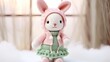 Soft white crocheted bunny, cuddly children's toy, adorable bunny knitted toy in clothes.