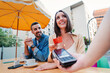 © Jose Calsina - Happy couple paying the bill of the coffee shop using a contactless creditcard payment. Young adult customer woman doing a purchase on a restaurant to the cashier with a debit card. People spending