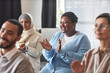 © Seventyfour - Young cheerful female student clapping her hands after report of speaker while sitting among intercultural listeners applauding to teacher