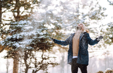 Wall Mural - Cheerful man enjoying a cold snowy day. Stylish man spends time outdoors. Season, Christmas, travel.