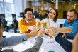 © maxbelchenko - Colleagues in the office celebrate the concluded deal with champagne and sparkling wine. A group of people with glasses of champagne having fun, relaxing in the office. Concept of work, holiday.