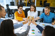 © maxbelchenko - Colleagues in the office celebrate the concluded deal with champagne and sparkling wine. A group of people with glasses of champagne having fun, relaxing in the office. Concept of work, holiday.