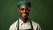 Portrait of a smiling african american male chef isolated on solid green background. Banner, copy space