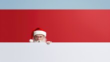  A Man In A Santa Claus Hat Peeking Over A White Board With A Red And White Stripe In Front Of Him.