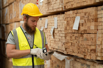 Caucasian businessman checking stock timber with bar code scanner at wood factory 