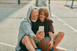© Marko Geber - Grandfather and grandson taking a selfie on a smart phone while resting from playing basketball outdoors on a basketball court in the city