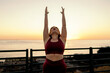 Plus-size woman in a yoga pose feeling empowered against a beautiful sunset backdrop, promoting a body-positive lifestyle.