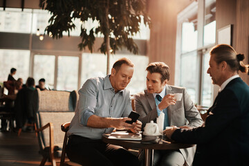 Wall Mural - Businessmen Engaged in Discussion Over Coffee