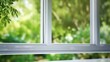© Chingiz - Freshly installed plastic PVC window with a white metal frame in a contemporary home, capturing a blurred background of lush green trees. An advertising concept portraying modern architecture