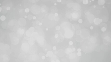 Abstract video background with shimmering white and gray bokeh light rings.