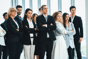 Wall Mural - Successful business people standing together showing strong relationship of worker community. A team of businessman and businesswoman expressing a strong group teamwork at the modern office. Jivy