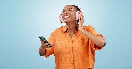 Wall Mural - Dance, headphones and black woman with phone in studio to celebrate freedom, karaoke party and audio on blue background. Excited model listening to mobile music, radio and singing sound with energy