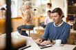 © JackF - Concentrated male designer preparing new project on laptop, sitting in cozy cafe with cup of coffee