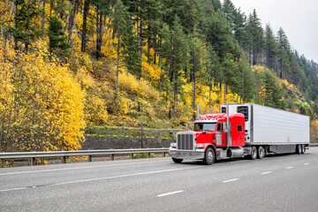 Wall Mural - Red classic long hauler American big rig semi truck transporting frozen cargo in loaded reefer semi trailer driving on the autumn highway road in Columbia River Gorge