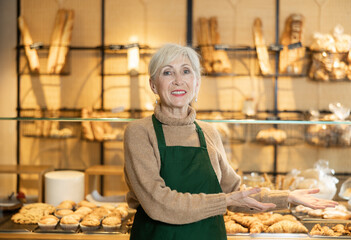 Cheerful mature female baker welcoming everyone into her bakery