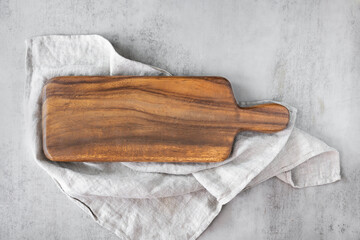 Wooden cutting board with linen napkin on marble table