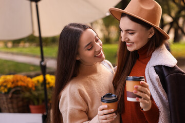 Wall Mural - Happy friends with paper cups of coffee outdoors, space for text