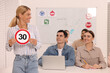 Teacher showing Speed Limit road sign during lesson in driving school