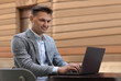 © New Africa - Handsome man working on laptop at table in outdoor cafe
