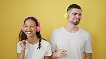 Wall Mural - Joyous beautiful couple dancing together, lost in music on yellow isolated background, lovely expression of love, lifestyle and fun!