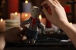 Woman stabbing voodoo doll with pin at table, closeup. Curse ceremony