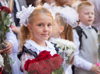 Wall Mural - The first time in the first class! A first-grader girl in a beautiful elegant modern school uniform on the Day of Knowledge at school.