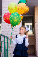 Wall Mural - The first time in the first class! A first-grader girl in a beautiful elegant modern school uniform on the Day of Knowledge at school.