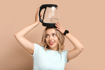 Wall Mural - Funny young woman with modern electric kettle on beige background