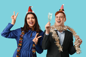 Sticker - Young couple with Christmas tinsel and glass of champagne on blue background