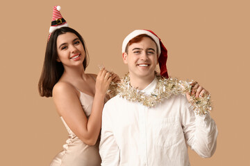 Sticker - Happy young couple with Christmas tinsel on brown background