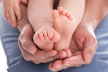 Father's Hands Holding Feet Of His Baby