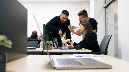 Group of businesspeople, mates involved in teamwork use laptop, look at device screen, consider new business program, corporate software, look interested, engaged in collaborative project discussion